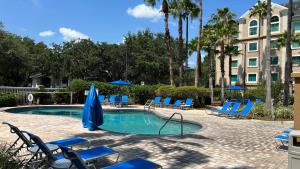 a swimming pool with blue chairs and umbrellas at HSO - Family Apartments Close to Disney World & Universal in Orlando