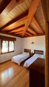 two beds in a large room with wooden ceilings at Villa Artegoikoa in Ibarrangelu