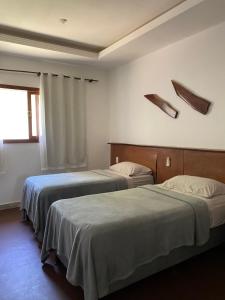 two beds in a hotel room with a window at Country Club Pititinga in Pititinga