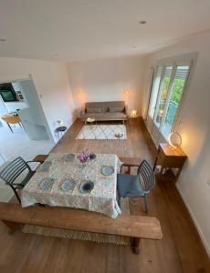 a living room with a table and a couch at La maison bleue vacance et jardin, la mer à 550 m in Blainville-sur-Mer