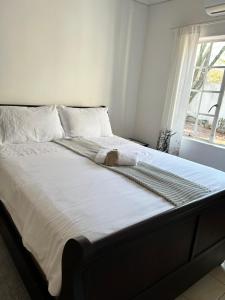 a bedroom with a large bed with white sheets and a window at Swinburn’s Rest in Lobatse