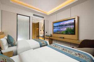 a hotel room with two beds and a flat screen tv at Oriental Sundar Hotel near China-Japan Friendship Hospital-Bird's Nest and Water Cube-Yonghe Palace-Nanluoguxu Alley in Beijing