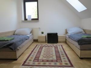 two beds in a room with a rug on the floor at AirSpot Balice in Cholerzyn