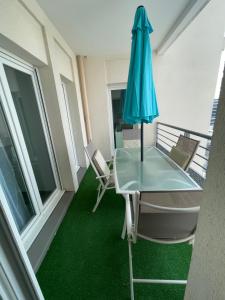 a glass table and chairs on a balcony with an umbrella at Appartement 4P, au pied de toute commodité in Créteil