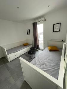 a white bedroom with two beds and a window at Appartement 4P, au pied de toute commodité in Créteil