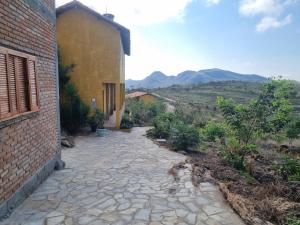 a stone walkway next to a building with mountains in the background at Pousada Trilhas de Gigantes in Itumirim