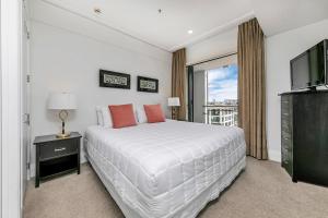 a white bedroom with a large bed and a television at Exquisite Sun Soaked Corner Apartment in Auckland +74 photos