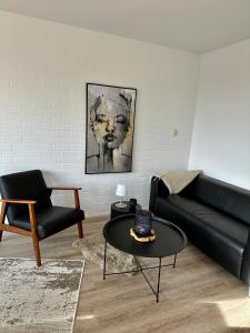 ein Wohnzimmer mit einem schwarzen Sofa und einem Tisch in der Unterkunft Bungalow kleine Deichperle neu ab Mai 24 Internet in Lemmer