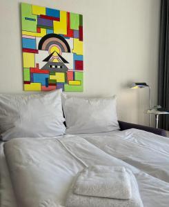 a bedroom with a white bed with a painting on the wall at NeuKlosterhof App. 18 in Pelzerhaken
