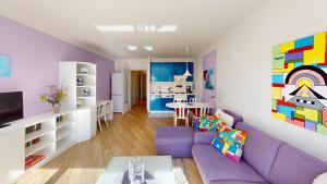 a living room with a purple couch and a kitchen at NeuKlosterhof App. 18 in Pelzerhaken
