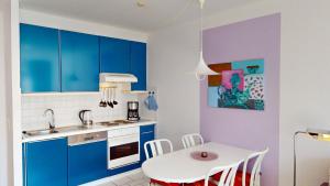 a kitchen with blue cabinets and a white table at NeuKlosterhof App. 18 in Pelzerhaken +19 photos