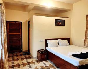 ein Schlafzimmer mit einem Bett und einer Tür in einem Zimmer in der Unterkunft Suncrest Wood Stayz in Alibag