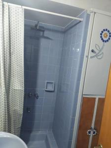 a bathroom with a shower with blue tile at MAILY Guest House in Alta Gracia