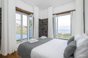 a bedroom with a large bed and large windows at Casas da Luz by Madeira Sun Travel in Ponta do Sol