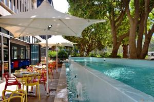 una piscina con mesas, sillas y una sombrilla en Fountains Hotel en Ciudad del Cabo
