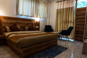 a bedroom with a bed and two chairs and a window at Winterstone studio in McLeod Ganj