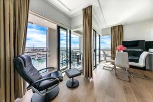 a living room with a table and chairs and a piano at Exquisite Sun Soaked Corner Apartment in Auckland