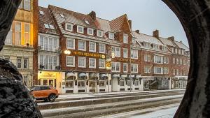 een raam met uitzicht op een straat met gebouwen bij Restaurant Hotel Goldener Adler in Emden