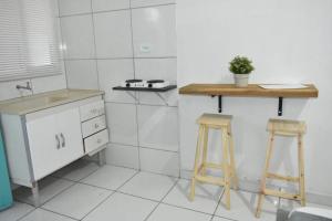 cocina con 2 taburetes de madera y lavamanos en Villagio Vistamar Ilha Comprida en Ilha Comprida