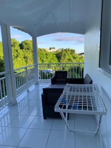 een veranda met een bank en een tafel op een balkon bij Maison dans les hauteurs in Le Gosier