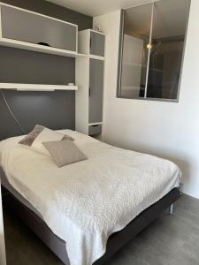 um quarto com uma cama com lençóis brancos e um espelho em Appartement Studio 35 m2 face à l'Ocean em Saint-Brévin-les-Pins