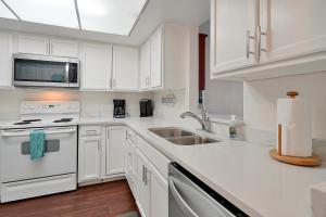 a white kitchen with a sink and a stove at Direct Oceanfront Condo Amazing Views Cocoa Beach in Cocoa Beach