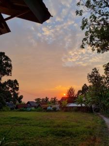 a sunset over a field with a house at Tetebatu Sama Sama Bungalows in Tetebatu