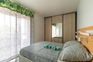 ein Schlafzimmer mit einem Bett und einem großen Fenster in der Unterkunft Port Royal T2 Cosy parking Centre Plage in Le Grau-du-Roi