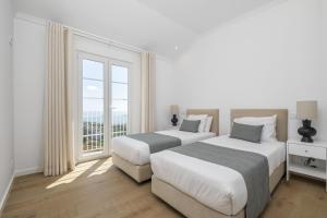 two beds in a white room with a window at Casas da Luz by Madeira Sun Travel in Ponta do Sol