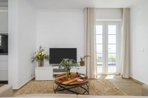 a living room with a table and a tv at Casas da Luz by Madeira Sun Travel in Ponta do Sol