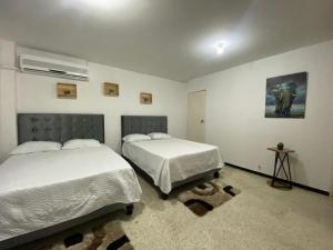 卡利的住宿－APARTAMENTO ESTADIO，一间卧室设有两张床,墙上挂着一幅画
