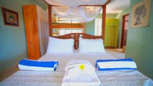 een slaapkamer met 2 bedden met blauwe en witte kussens bij The Tree House Bella Seaview Diani Beach Kenya in Diani Beach