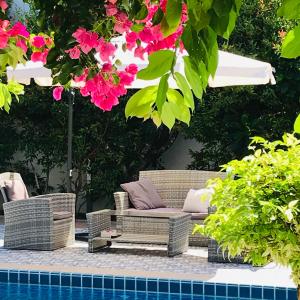 a patio with wicker chairs and flowers next to a pool at Guest House, shared pool, private bathroom and kitchen in Phuket Town