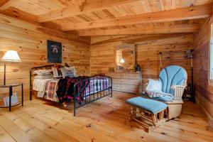 Dormitorio en cabaña de madera con cama y silla en The Willow Family Friendly country cabin Red River Gorge en Ravenna