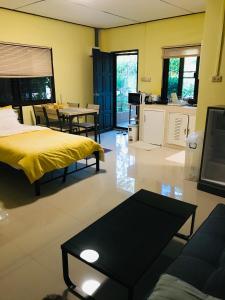 a living room with a yellow bed and a table at Guest House, shared pool, private bathroom and kitchen in Phuket Town
