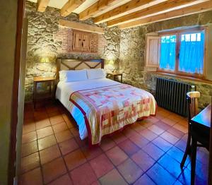 um quarto com uma cama grande num quarto de pedra em Saltus Alvus, casas 4 estrellas con encanto en Sotosalbos em Sotosalbos