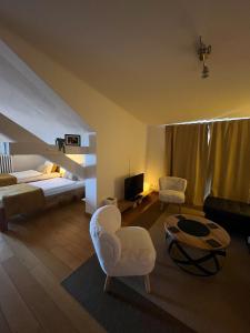 a living room with a bed and chairs and a television at BnB La Clemonie in Arzier