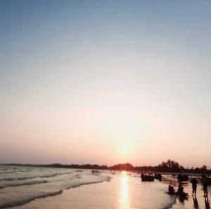 un grupo de personas en una playa al atardecer en Nhà Nghỉ Việt Thắng en Bàu Dòi