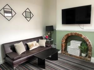 a living room with a brown leather couch and a fireplace at Large House near MediaCity, sleeps 13 with FREE Parking and Fast WIFI - Contractor and Long Stay Friendly - by IRWELL STAYS in Manchester