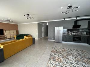 a living room with a yellow couch and a kitchen at Valentina Guest House in Tsandrypsh