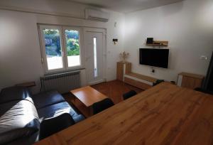 ein Wohnzimmer mit einem Tisch, einem Sofa und einem TV in der Unterkunft Apartments Dijana in Rab