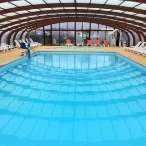 a large indoor swimming pool with blue water at Bungalow de 3 chambres avec piscine partagee jardin amenage et wifi a Onzain in Onzain