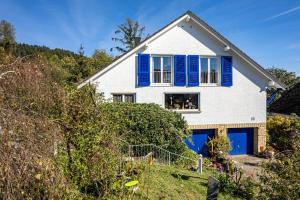 Casa blanca con persianas azules en Ferienwohnung Anne und Peter Bosch, en Alpirsbach