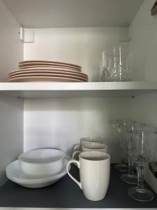 a kitchen shelf with plates and bowls and a coffee cup at Cozy Carmelite apartment in Vilnius