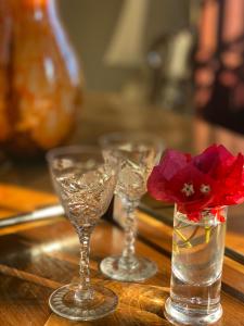 tres copas de vino en una mesa con una flor en un jarrón en Casa Palacio Ánima, en Jerez de la Frontera