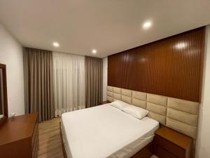 a bedroom with a white bed and a wooden wall at Royal Seaview Apartment in Durrës