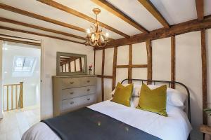 a bedroom with a bed with yellow pillows and a ceiling at Luxury Cotswold Cottage with hot tub in Stow on the Wold! in Stow on the Wold