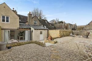 a backyard of a house with a stone wall at Luxury Cotswold Cottage with hot tub in Stow on the Wold! in Stow on the Wold
