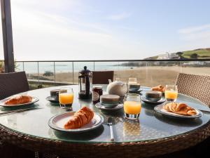a table with a breakfast of croissants and orange juice at 4 Burgh Island Causeway in Kingsbridge