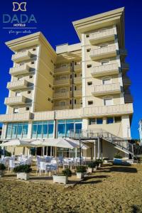 um grande edifício na praia com cadeiras e guarda-sóis em Hotel Imperial Beach - Dada Hotels em Rimini